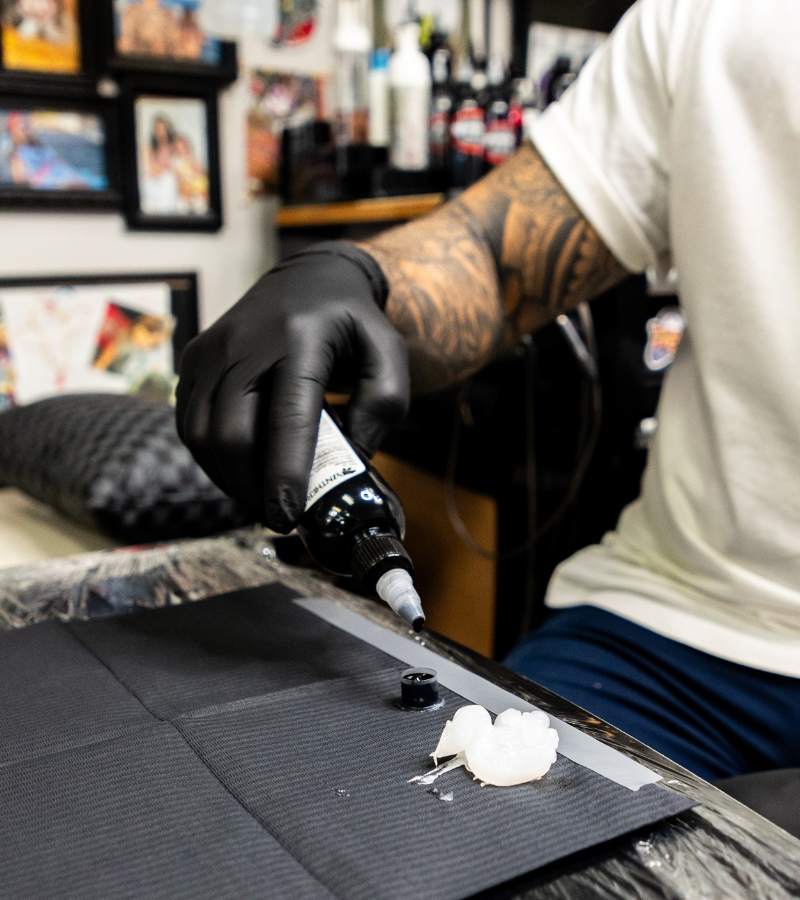 Tattoo Artist Poring Black Ink into Ink Cap