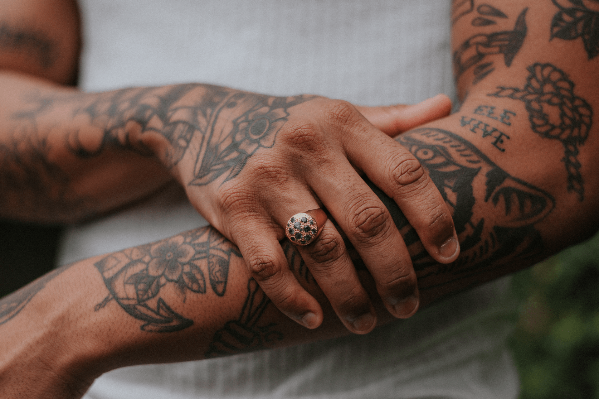 Close-up of a woman's tattooed arms, with one hand gently holding her forearm